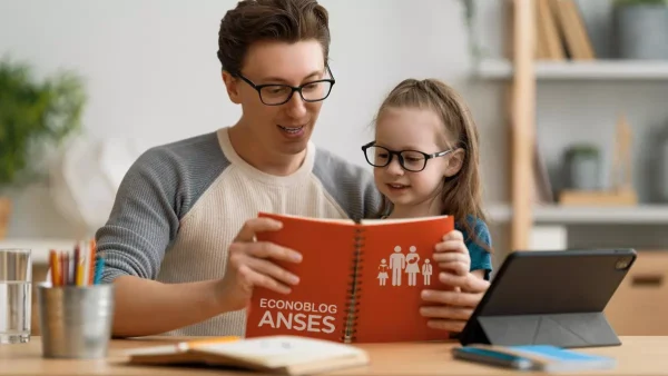 Padre con hijo y cuaderno de AUH y Anses