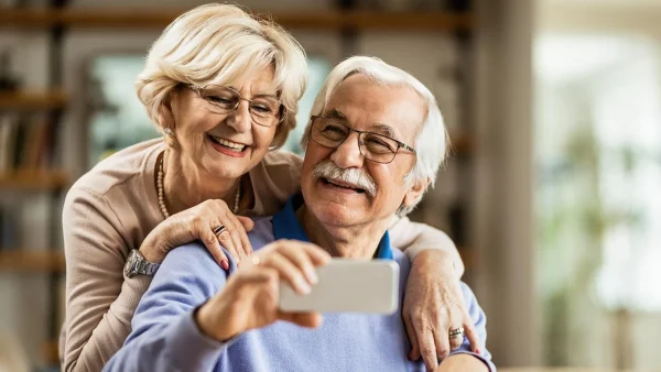 Jubilados felices con celular en la mano