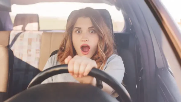 Mujer conduciendo un auto siendo sorprendida