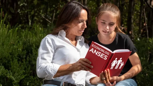 Madre con su hija leyendo un libro del SUAF de Anses