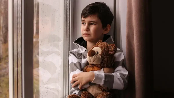 Niño triste abrazado a su oso