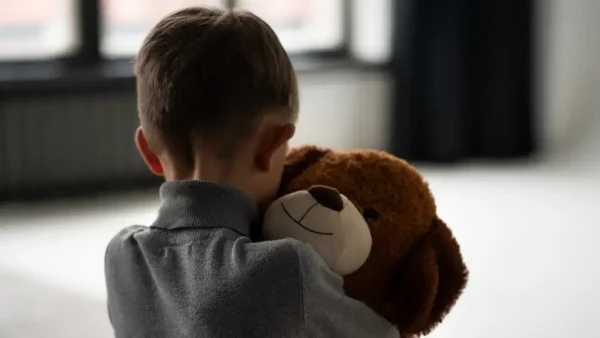 Niño triste abrazando a su oso