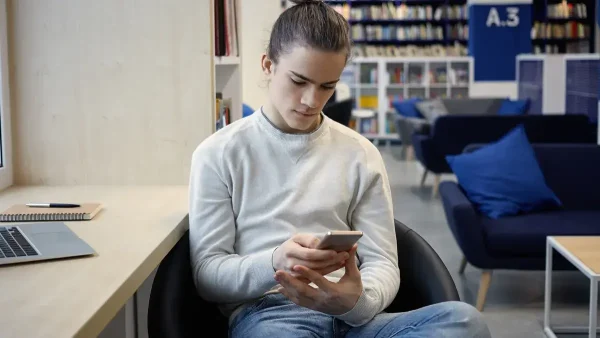 Estudiante pensando con su celular