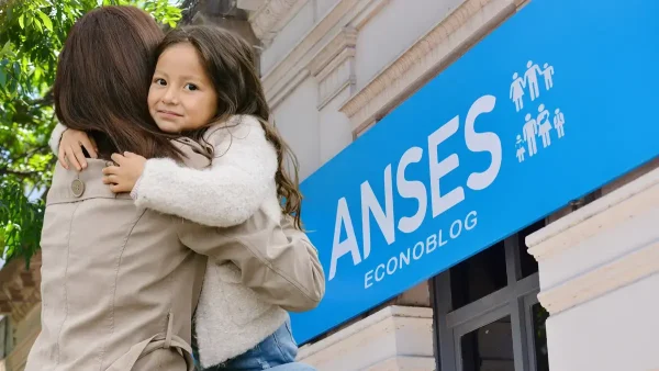Madre junto a cartel de SUAF y AUH en Anses