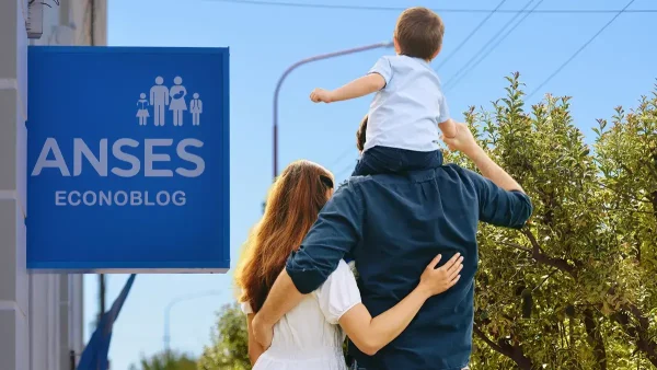 Familia de la AUH frente a cartel de Anses