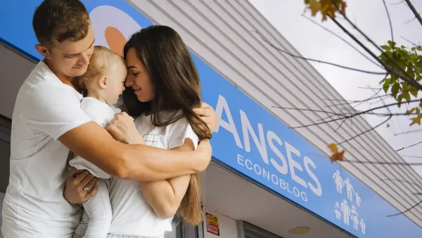 Familia con bebé junto a cartel de Anses para AUH y SUAF