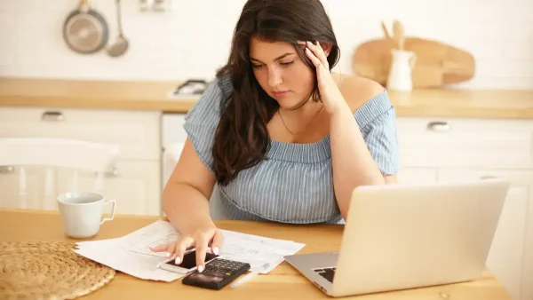 Mujer preocupada haciendo cuentas con calculadora