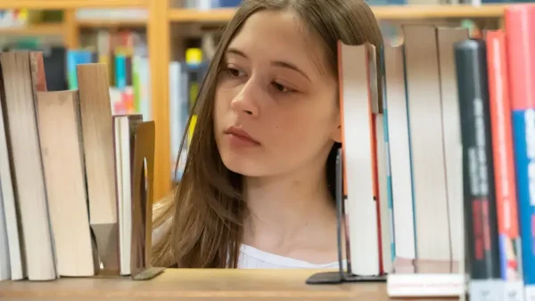 Estudiante pensando entre libros